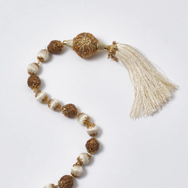 Close-up of greenery along the garland on this Ivory and Gold Beaded Ball Hanging Trim