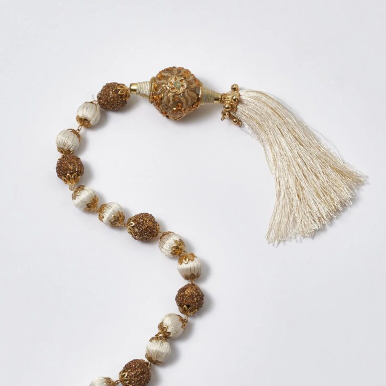 Close-up of greenery along the garland on this Ivory and Gold Beaded Ball Hanging Trim
