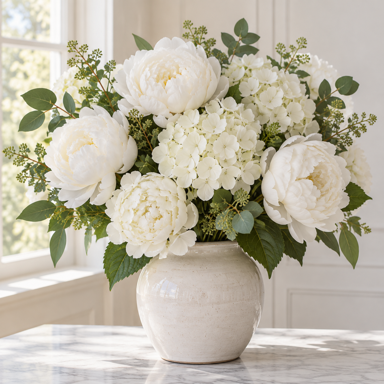 White artificial peonies and hydrangeas in a ceramic vase by a bright window
