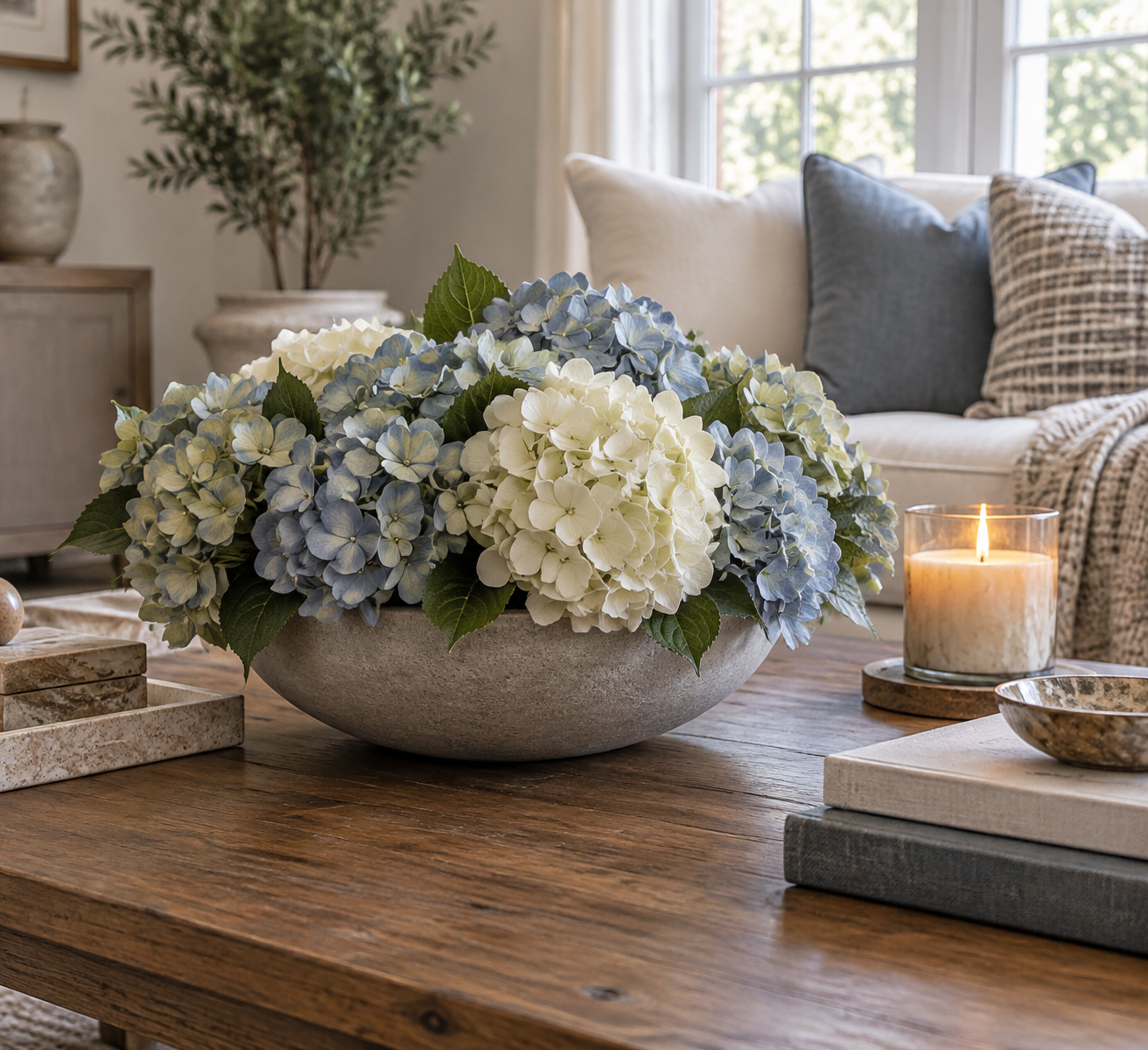 Low bowl of artificial hydrangeas on a coffee table with books