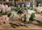 Flat lay of silk wedding flower stems tools and ribbon on a work table ready for assembly