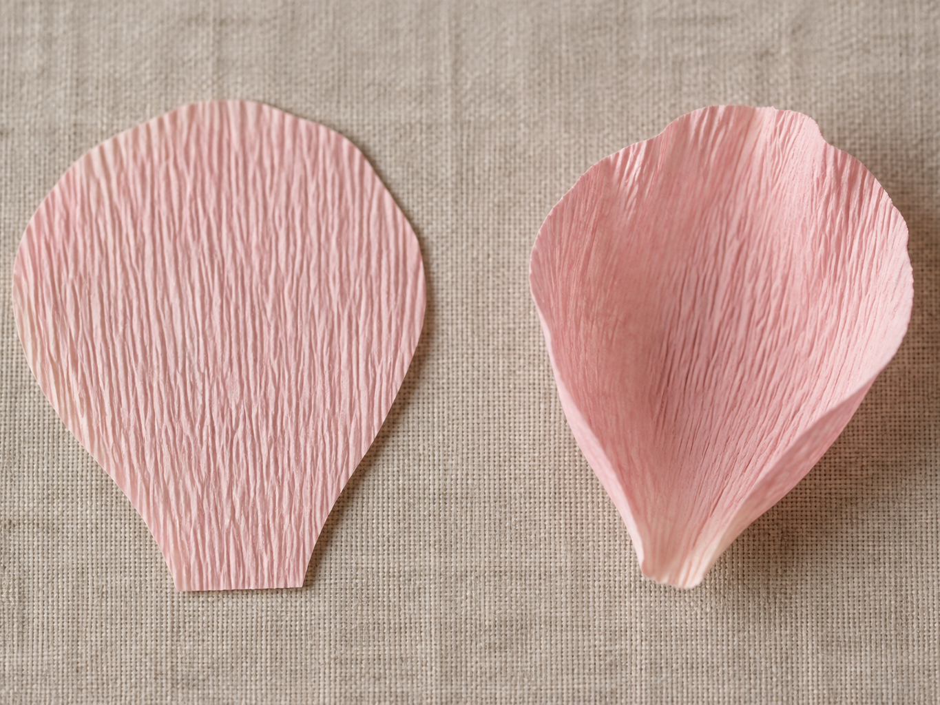 Fingers cupping and stretching a crepe paper petal to give it a curved shape