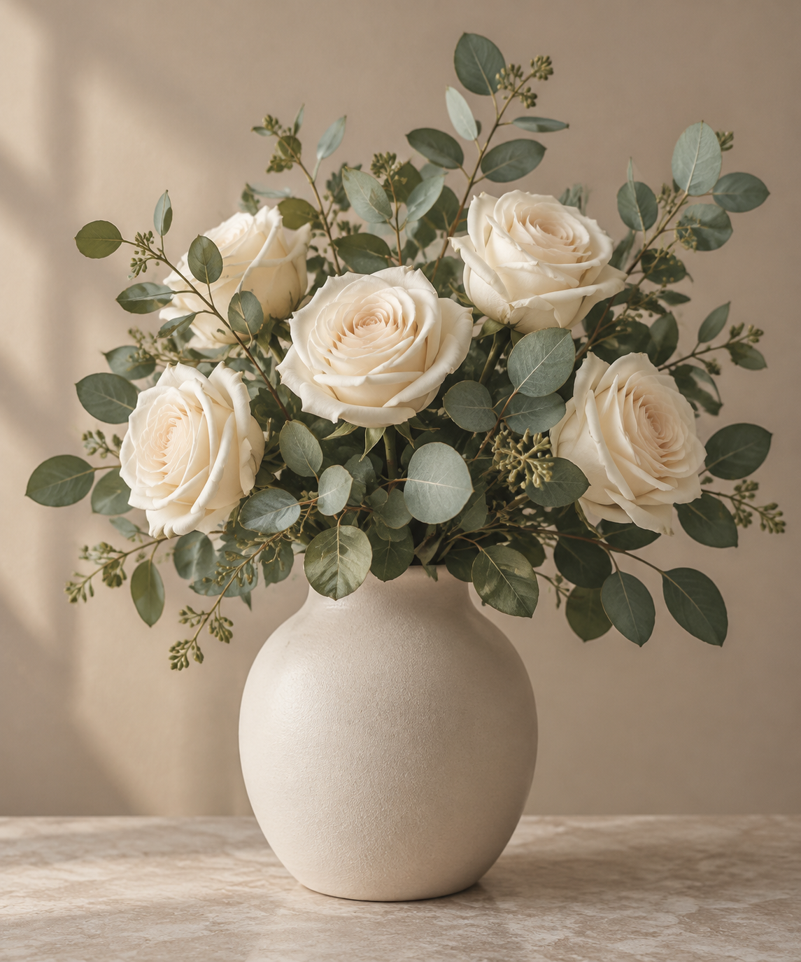 Cream roses and sage eucalyptus in a modern ceramic vase