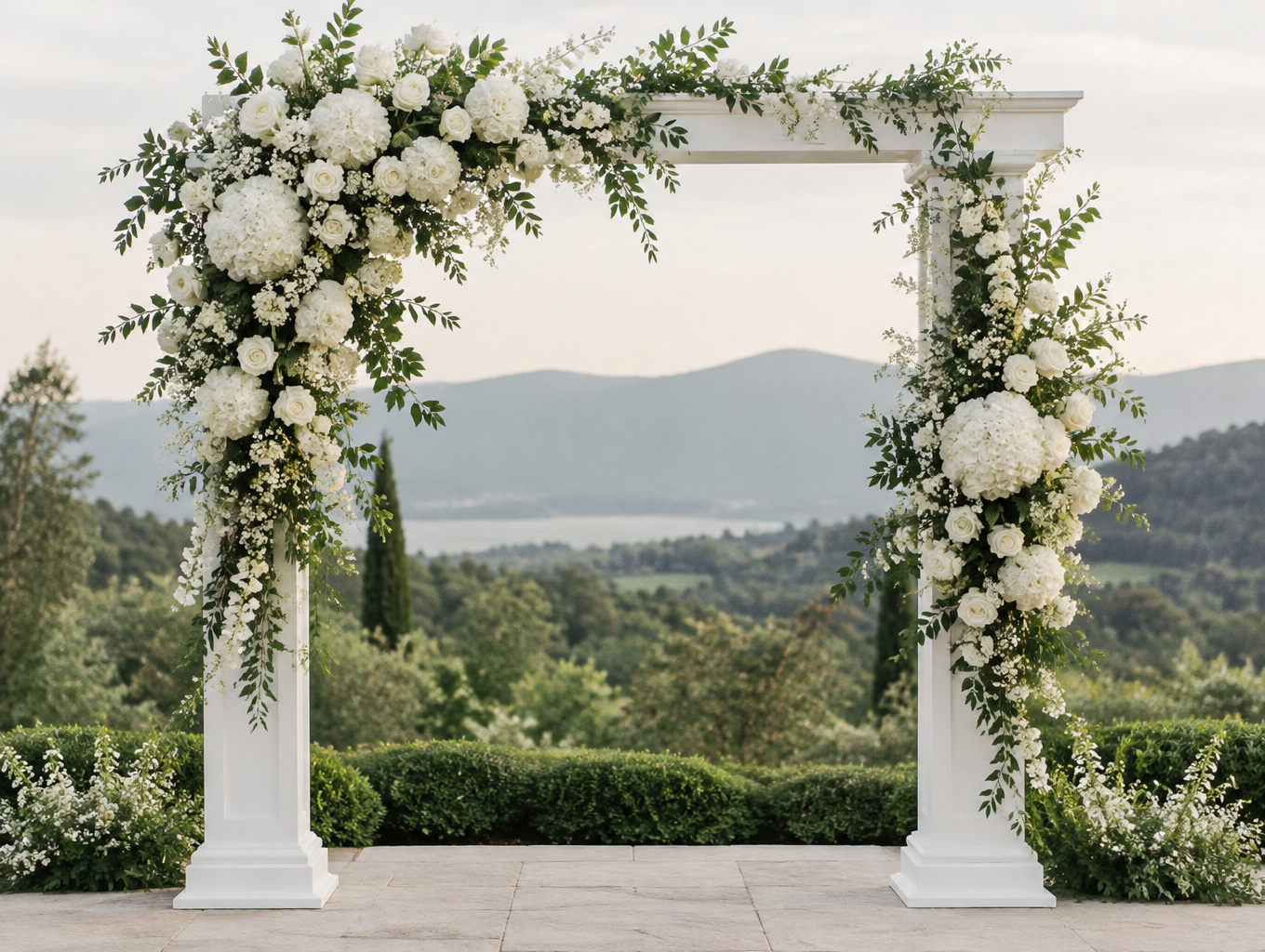 An all-white ceremony arch with layered white blooms and greenery